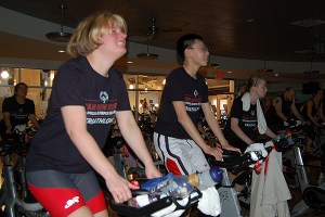 Three Special Olympics athletes train on stationary bikes in a gym. 